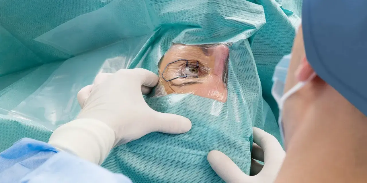 Chirurg w rękawiczkach przygotowuje oko pacjenta do zabiegu laserowej korekcji wzroku.