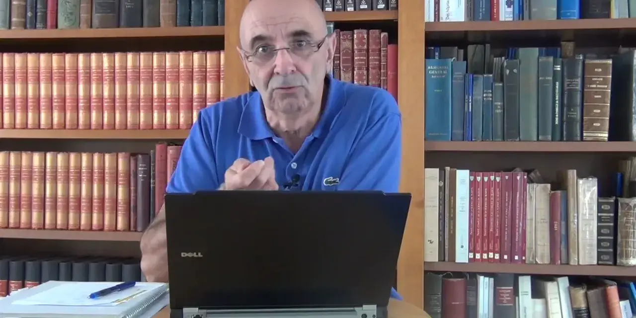 Un homme parle devant un ordinateur portable, entouré de rayonnages remplis de livres anciens, rappelant les archives départementales 85.