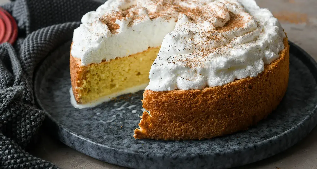 Tarta tres leches esponjosa, cubierta de merengue y espolvoreada con canela. Se ve deliciosa y lista para disfrutar.