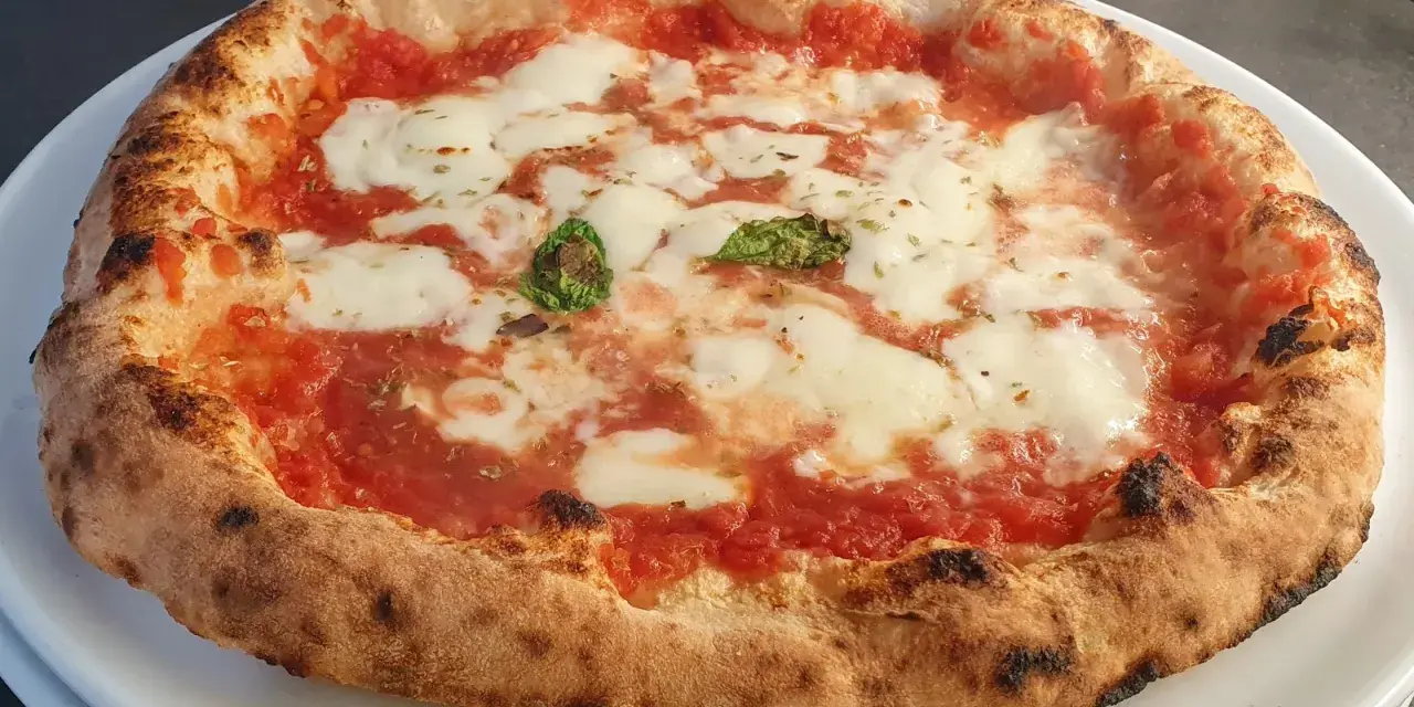 Pizza a lunga lievitazione con pomodoro, mozzarella filante e basilico fresco. Croccante fuori, soffice dentro, un vero capolavoro.