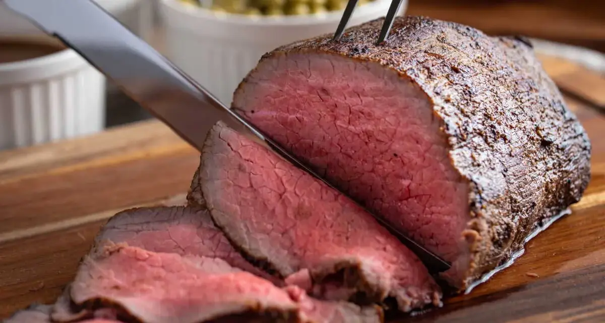Un délicieux roti de boeuf, coupé en fines tranches rosées, est prêt à être servi avec des accompagnements.