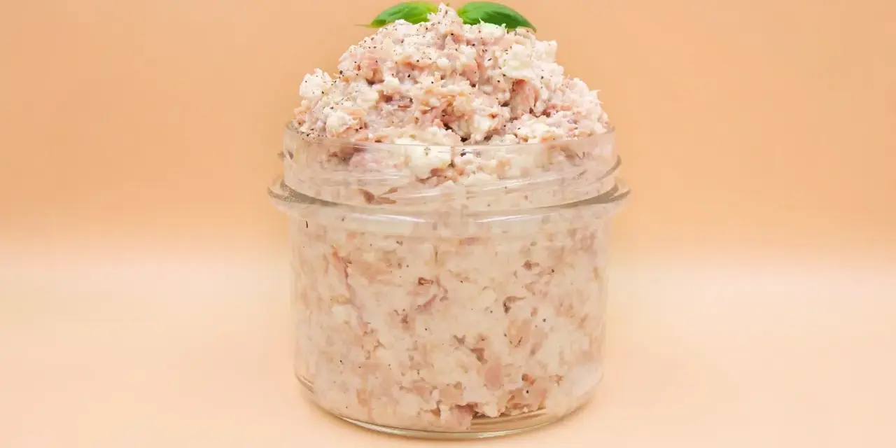 Pyszna pasta z tuńczyka i twarogu, doprawiona pieprzem, w słoiku, ozdobiona listkami bazylii. Idealna na kanapki.