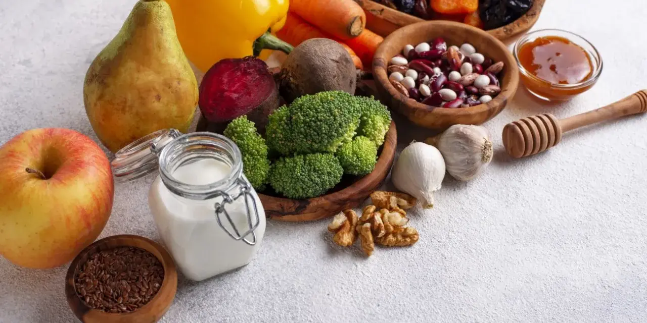 Składniki na zdrową dietę jelitową: jabłko, gruszka, brokuły, buraki, marchew, papryka, fasola, orzechy, czosnek, siemię lniane, jogurt, suszone owoce i miód.