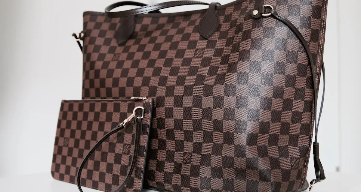 Duża torebka Louis Vuitton w kratkę, obok mniejsza kosmetyczka. Klasyczny wzór Damier Ebene.