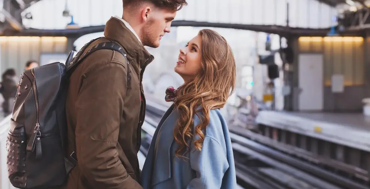 Un couple se regarde avec tendresse sur un quai de gare, un moment où l'on peut se sentir connecté à quelqu'un à distance.