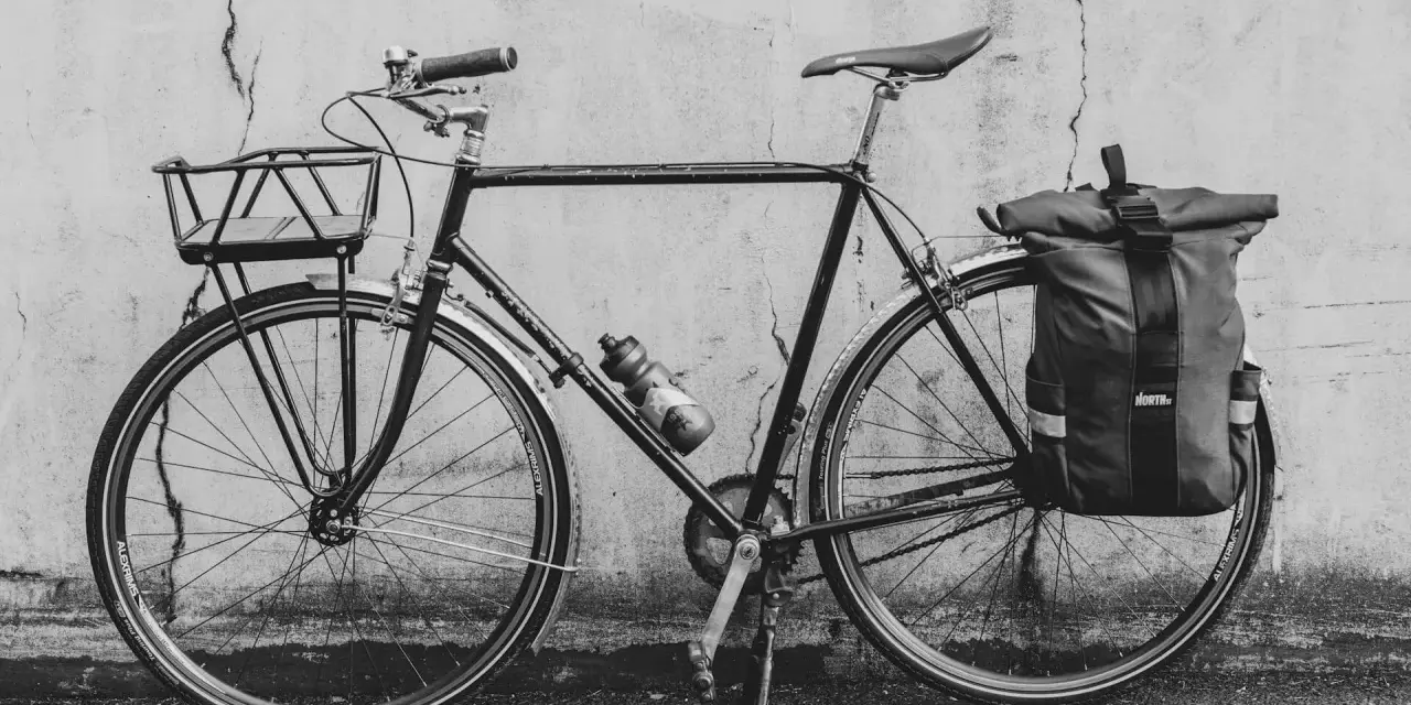Svart cykel med korg fram och väska bak, redo att montera pakethållare för äventyr.