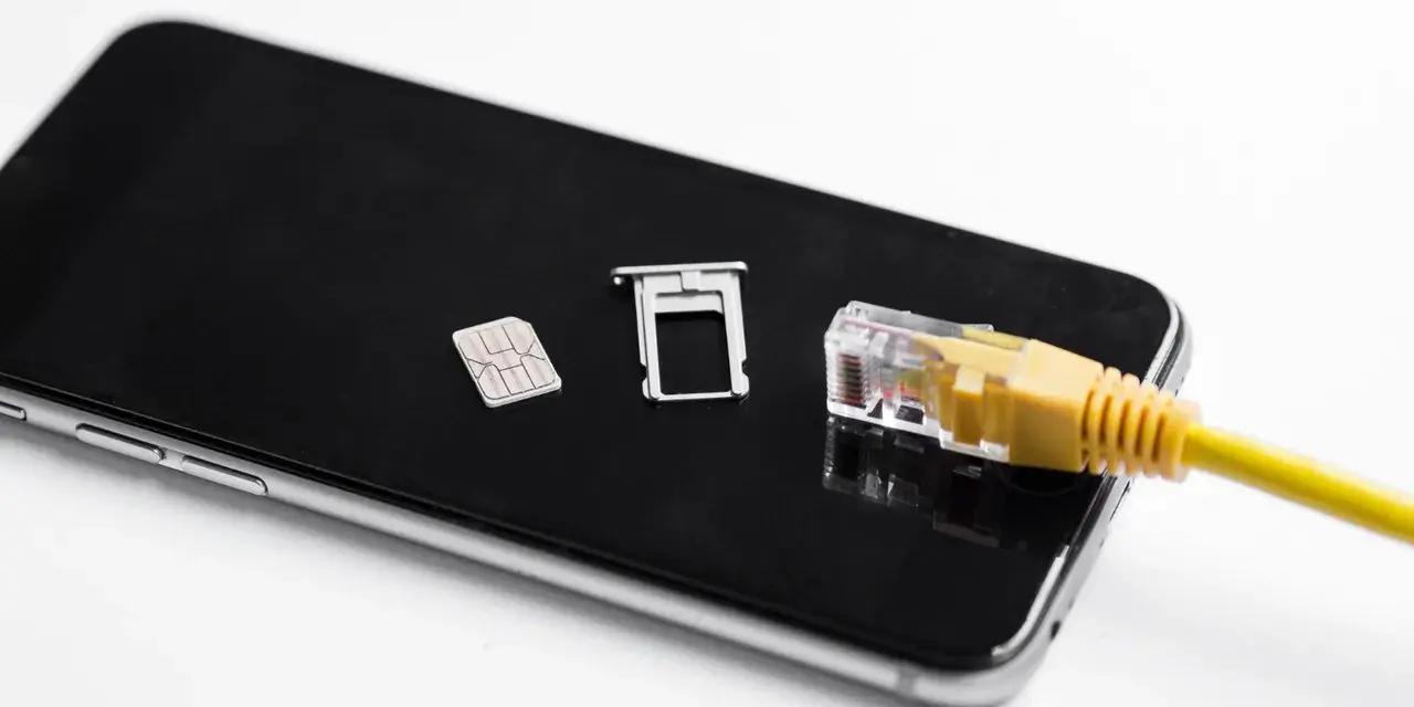 Smartfon z kartą SIM i tacką, podłączony żółtym kablem sieciowym. Możliwość play multisim.
