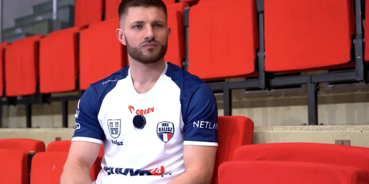 Marcel Sroczyk, zawodnik MKS Kalisz, siedzi na czerwonych trybunach.