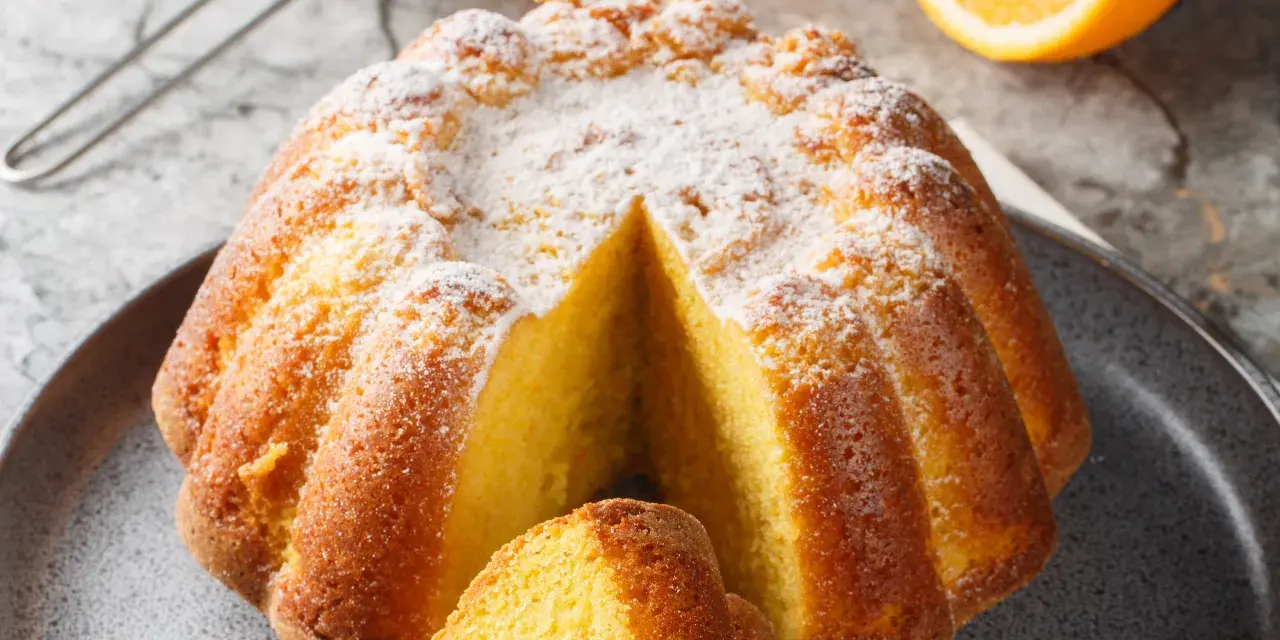 Una fetta di torta all'arancia morbidissima, cosparsa di zucchero a velo, pronta per essere gustata.