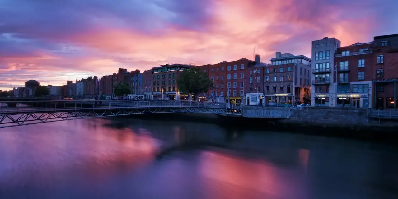 Zachód słońca nad rzeką Liffey w Dublinie. Widok na most i zabytkowe kamienice, idealne miejsce, by zobaczyć Dublin.