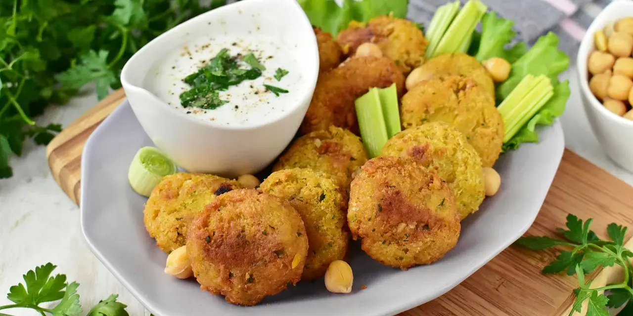 Pyszny falafel przepis na talerzu, podany z sosem jogurtowym, selerem i natką pietruszki. Idealna przekąska!