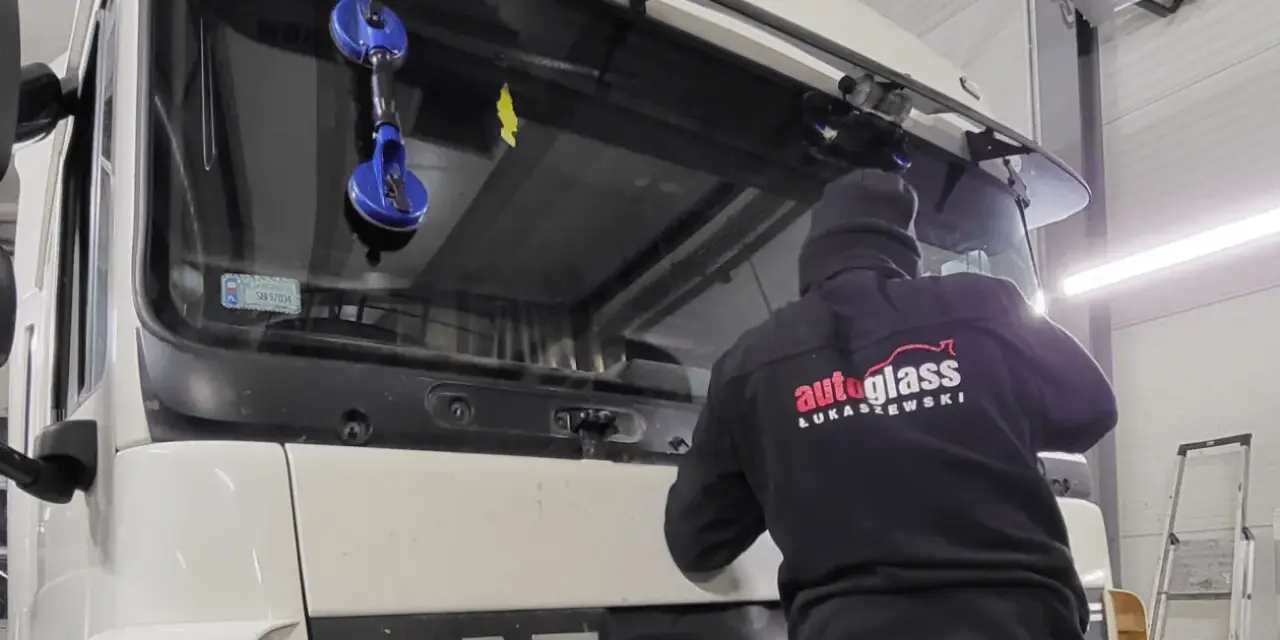 Montaż szyby w traktorze DAF. Pracownik firmy "Autoglass Łukaszewski" używa przyssawek do bezpiecznego osadzenia nowej szyby.