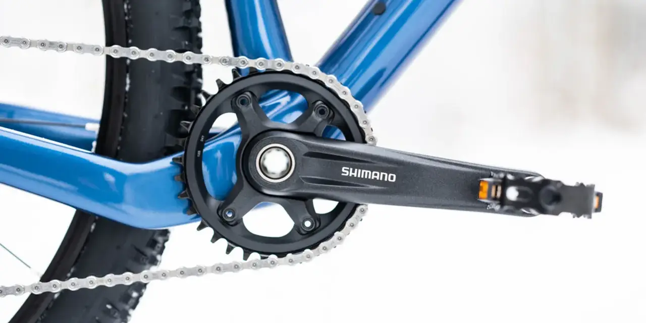 Jak odkręcić pedały w rowerze? Widok na korbę Shimano, łańcuch i fragment ramy roweru.