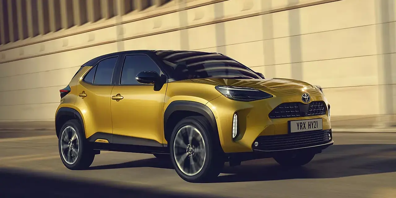 Złoty Toyota Yaris Cross Hybrid w ruchu. Dowiedz się, ile kosztuje Toyota Yaris Hybrid i odkryj jego zalety.