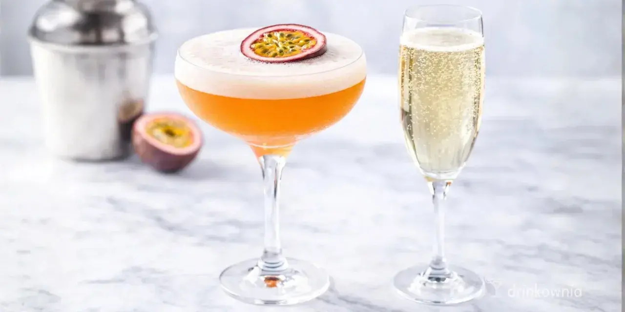 Pomarańczowy drink z pianką i marakują, obok kieliszek szampana. Idealny white lady drink na letnie popołudnie.