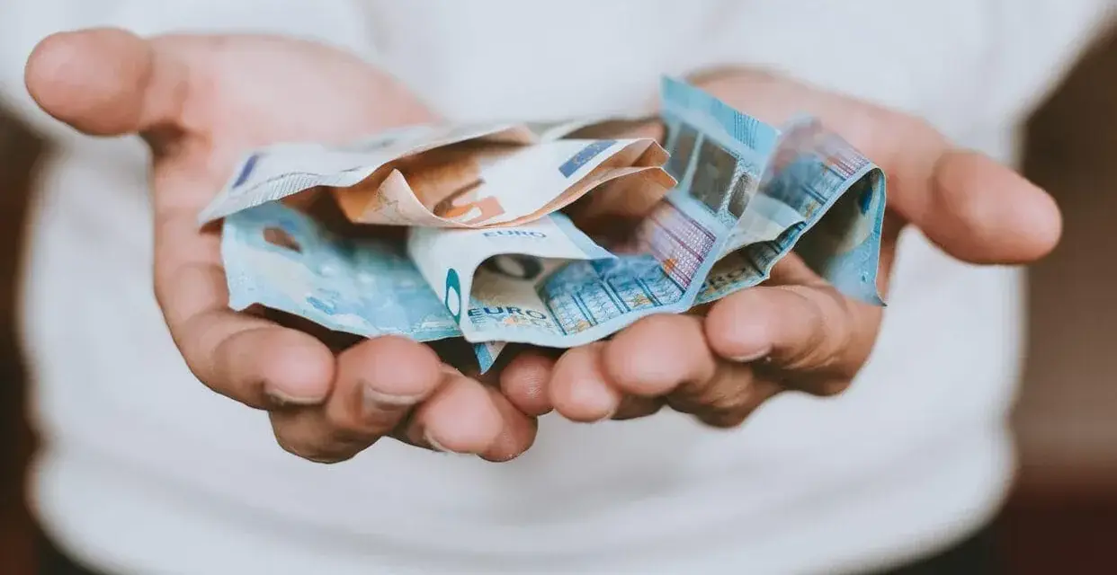 Hände halten zerknitterte Euro-Scheine. Das Geld ist für das geplante **auslandsjahr 3 monate** gedacht.