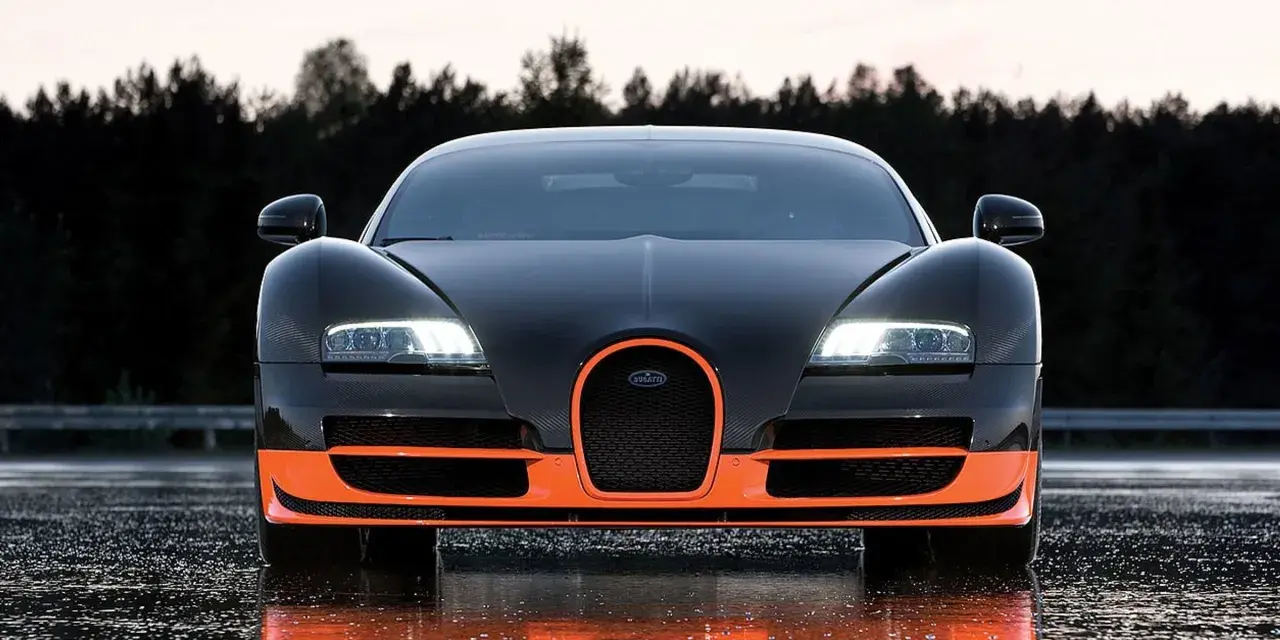 Czarny Bugatti Veyron z pomarańczowymi akcentami, gotowy do jazdy po mokrej nawierzchni.