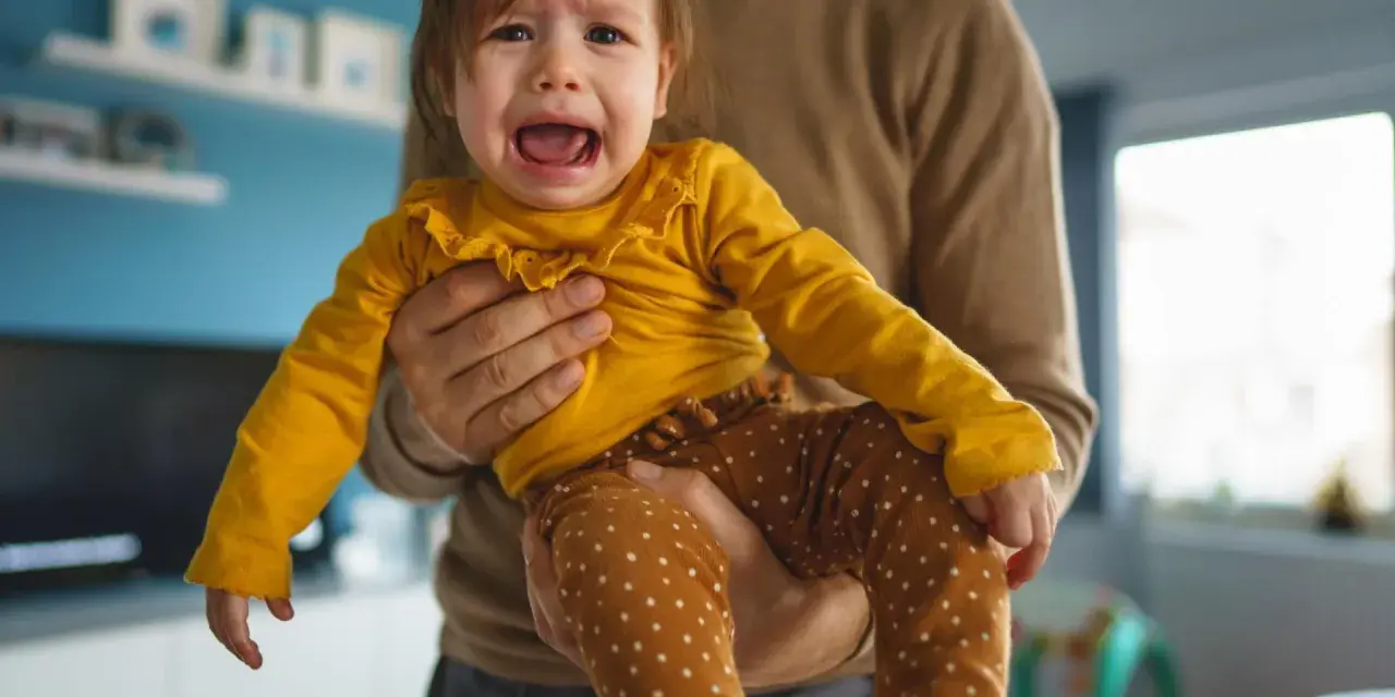Ein weinendes Kind (2 Jahre) wird von seinem Vater gehalten. Es sagt "Mama weg!" und ist untröstlich.