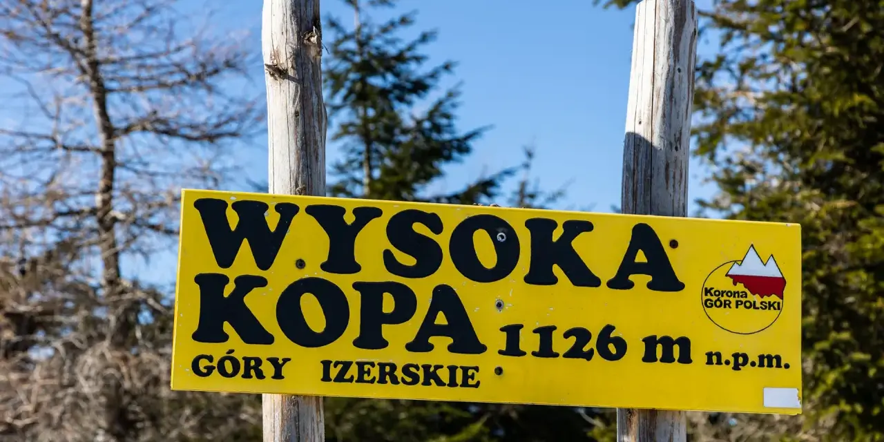 Żółta tablica informuje o szczycie Wysoka Kopa, najwyższym szczycie Gór Izerskich, na wysokości 1126 m n.p.m.