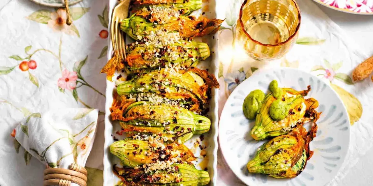 Deliziosi fiori di zucca al forno, ripieni e dorati, serviti su un piatto con un tocco di verde.