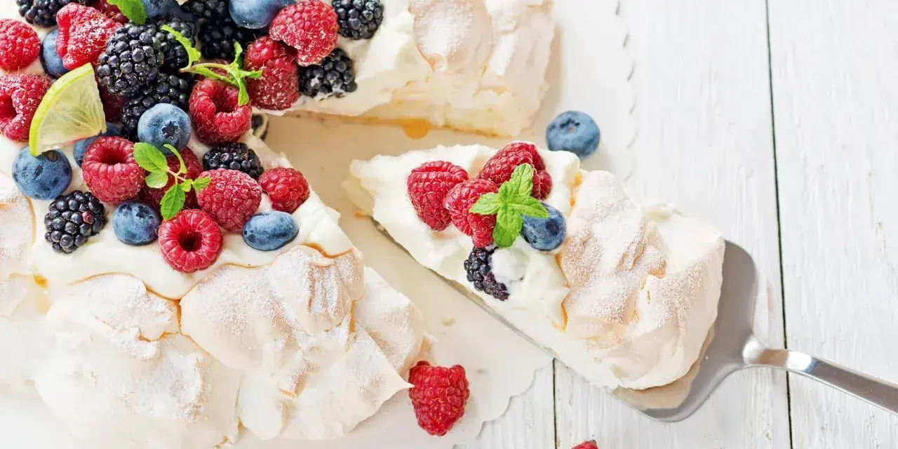 Beza pavlova która zawsze wychodzi, udekorowana świeżymi malinami, borówkami, jeżynami i plasterkami limonki.