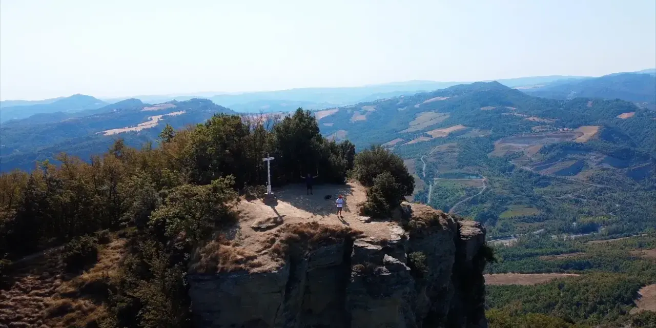 Due escursionisti celebrano la vetta raggiunta sul crinale, un momento clou del cammino della Via degli Dei in 5 giorni.