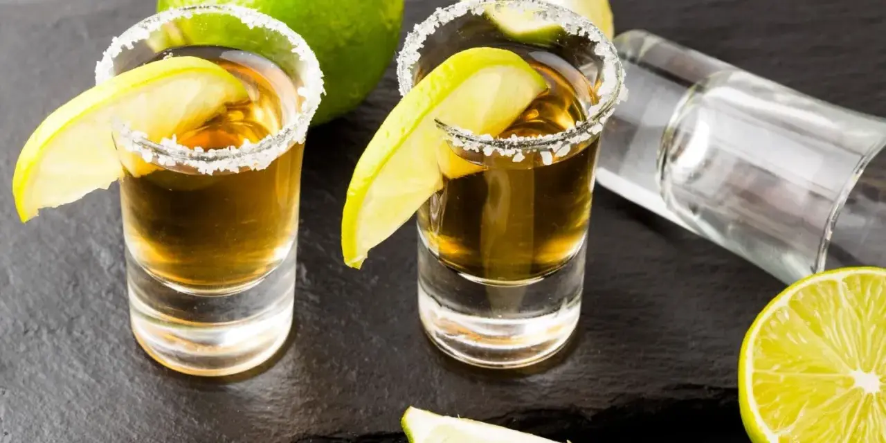 Dwa kieliszki tequili z solą i limonką, gotowe do degustacji. Czas sprawdzić, jak smakuje tequila!