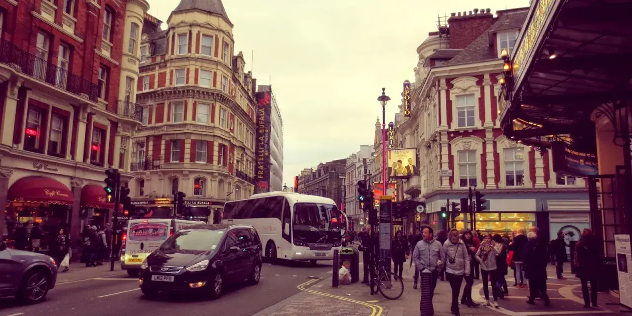 Tętniące życiem ulice Soho w Londynie, z charakterystyczną architekturą, autobusami i ludźmi spacerującymi po chodniku.
