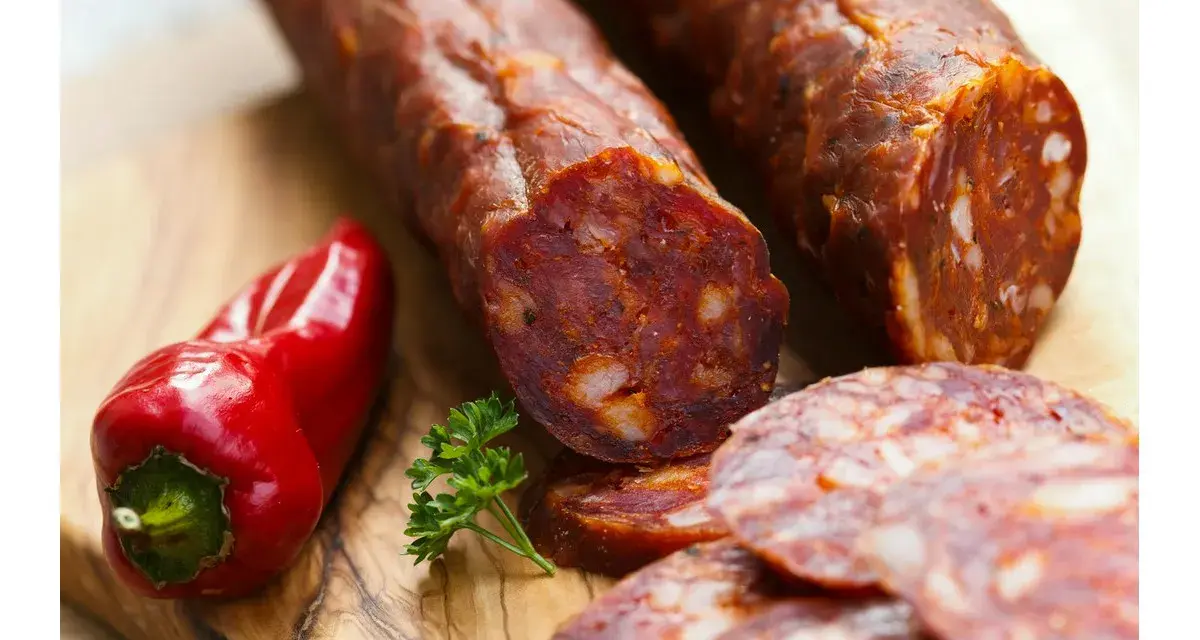 Kawałki pikantnego chorizo, czerwona papryczka i natka pietruszki na desce. Dowiedz się, chorizo co to jest!