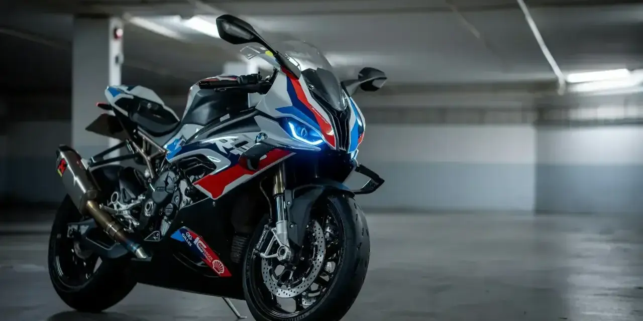 Sportowy motocykl BMW XR w barwach M, z niebieskimi światłami LED, gotowy do jazdy po torze.