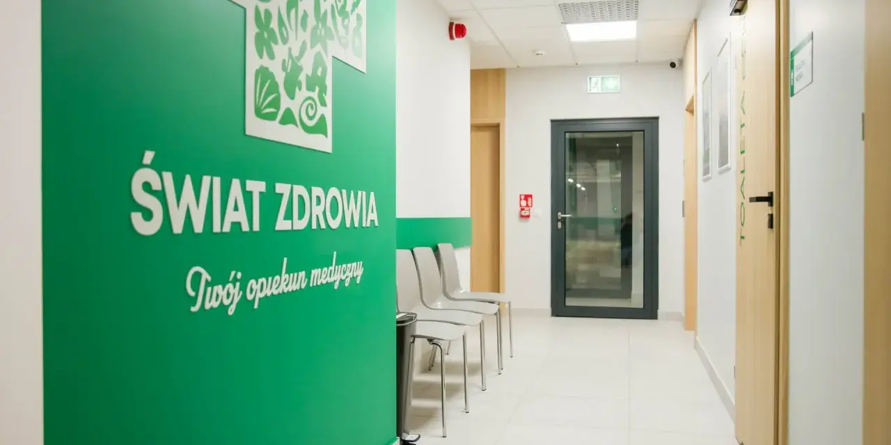 Zielona ściana z napisem "Świat Zdrowia" i logo, korytarz kliniki medycznej z drzwiami i krzesłami.