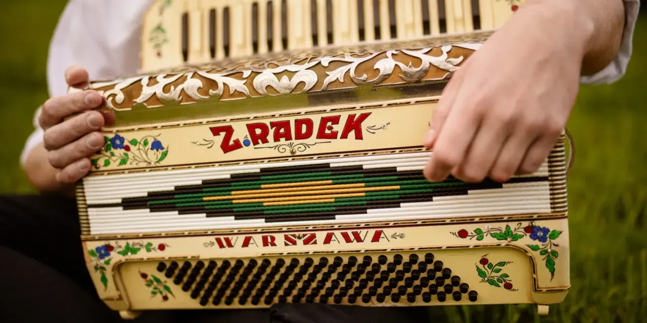 Dłonie grają na akordeonie "Z. Radek Warszawa", tworząc piękną harmonię.