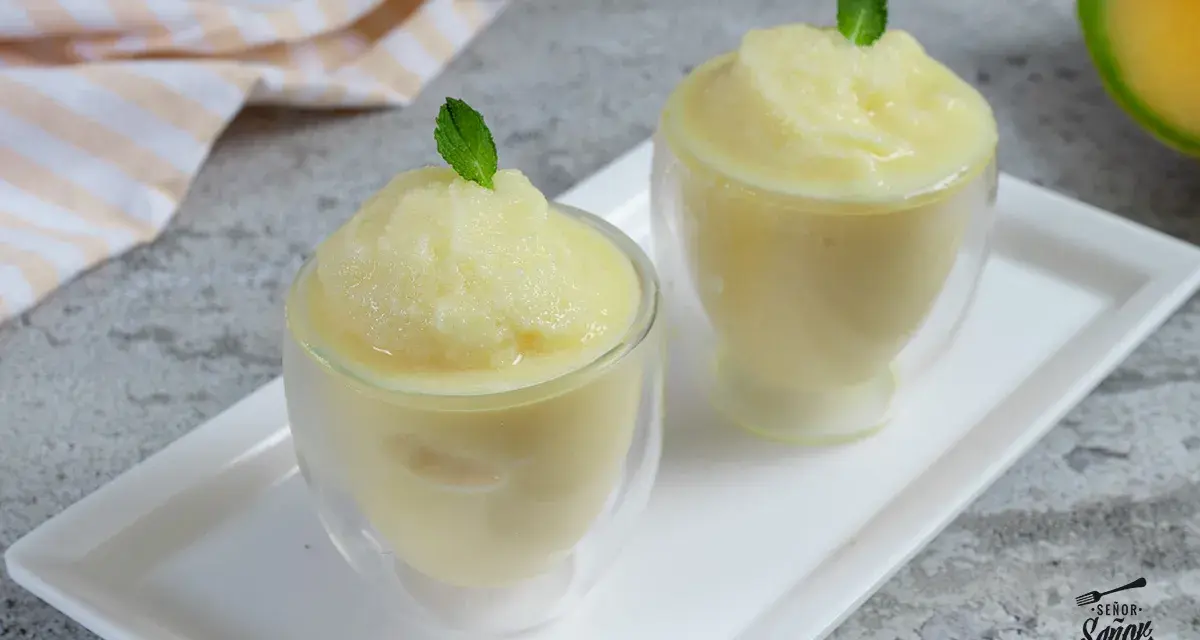 Dos copas de refrescante sorbete de melón, decoradas con hojas de menta, listas para disfrutar en un día caluroso.
