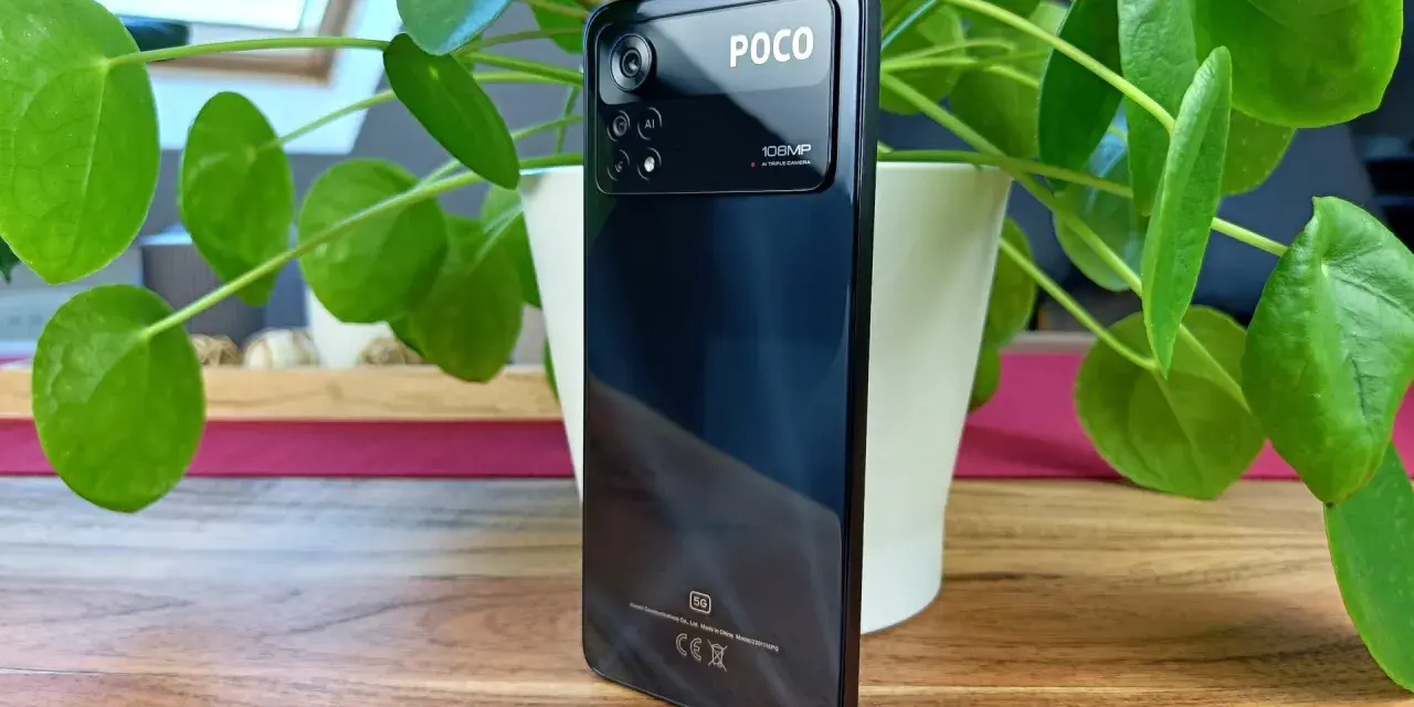Czarny POCO z aparatem 108MP, otoczony zielonymi liśćmi rośliny.