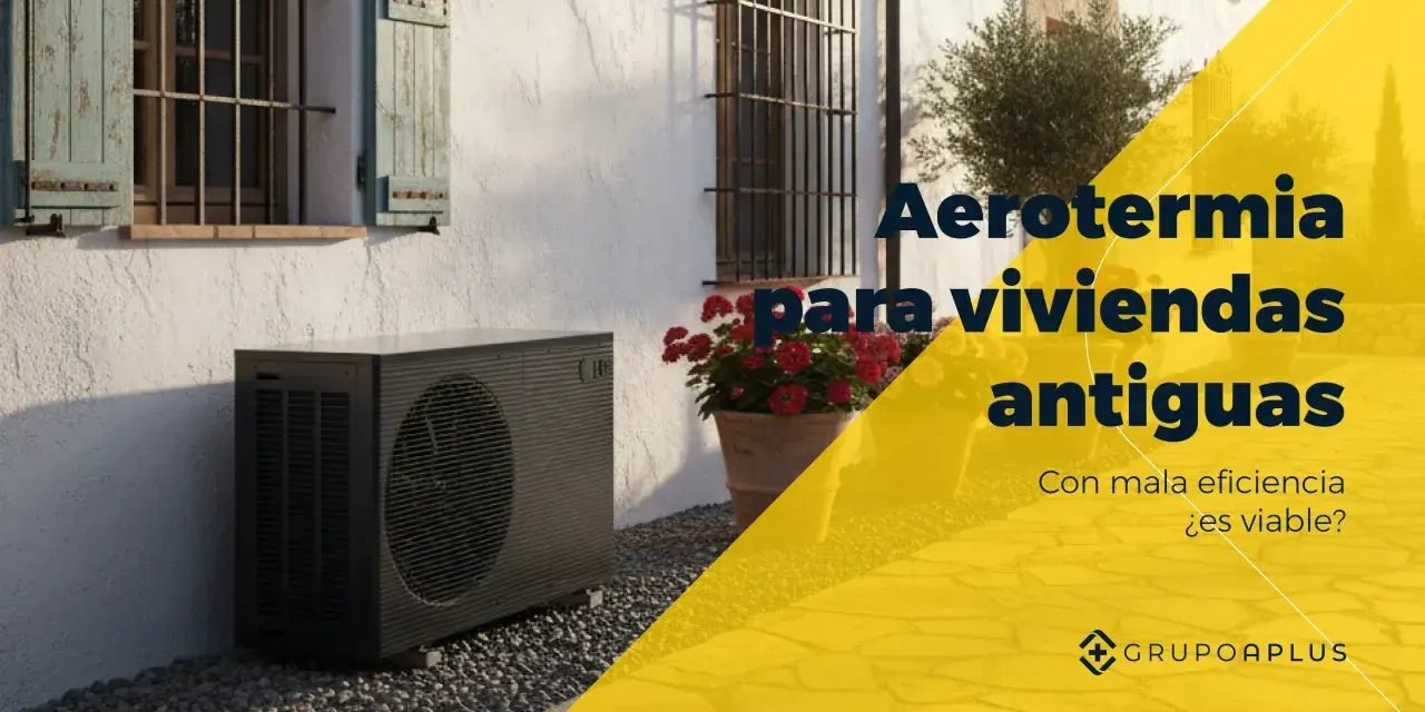 Unidad exterior de bomba de calor aire-agua junto a una casa antigua con flores. Aerotermia para viviendas antiguas.