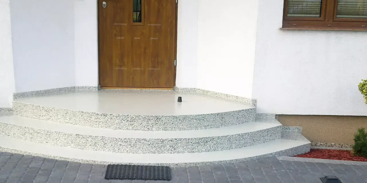 Schody i balkon z żywicy przed drzwiami wejściowymi do domu.