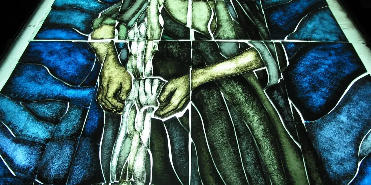 Fragment witrażu w stylu modernizm, przedstawiający postać w niebieskim i zielonym tle.