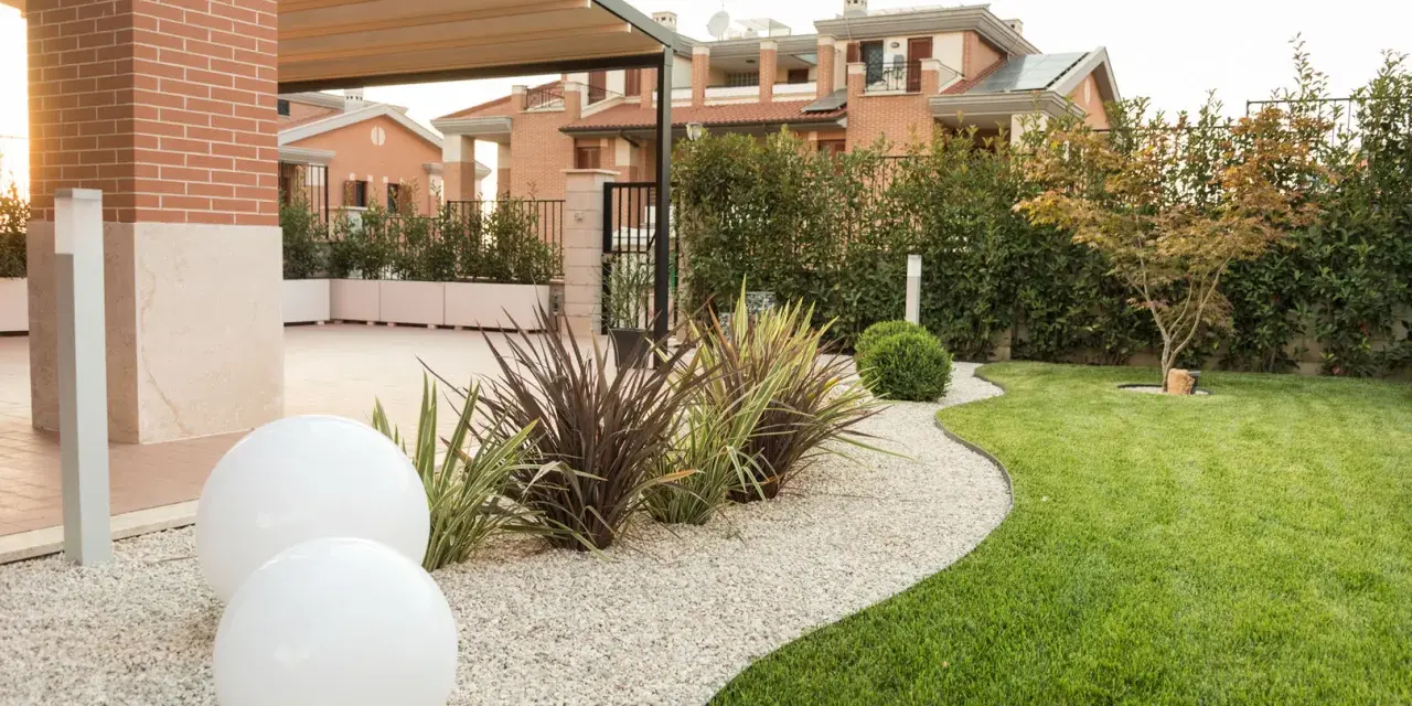 Giardino moderno con ghiaia bianca, sfere luminose e piante decorative. Belle idee giardino ingresso casa per un'accoglienza elegante.