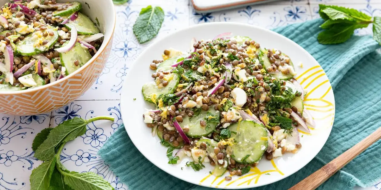 Salade de lentilles, concombre, oignon rouge et feta émiettée, garnie d'herbes fraîches. Un délice léger et coloré.