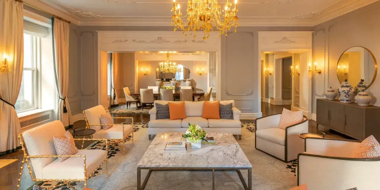 Elegancki salon z marmurowym stolikiem i złotym żyrandolem. Sprawdź hotel Plaza Nowy Jork ceny, by poczuć ten luksus.