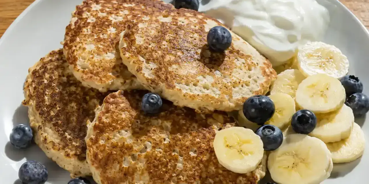En tallrik med bananpannkakor, blåbär, bananskivor och en klick yoghurt. Ett enkelt bananpannkaka recept för en god frukost.