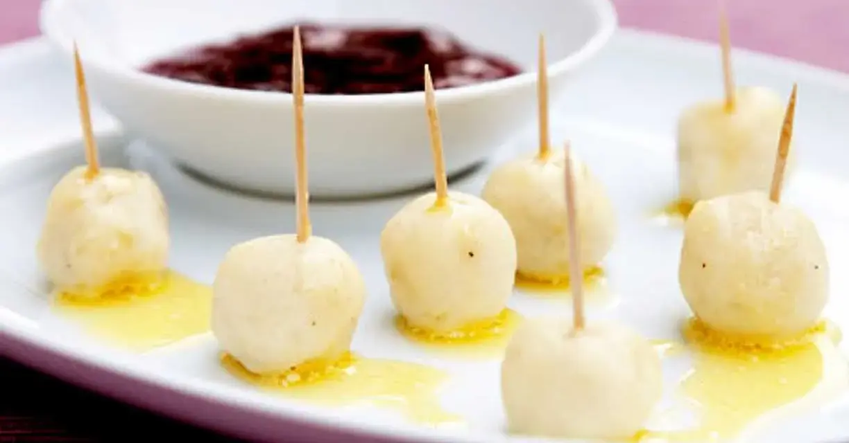 Små, gyllene kroppkakor med tandpetare, serverade med en skål mörk sylt. Ett spännande recept att prova!