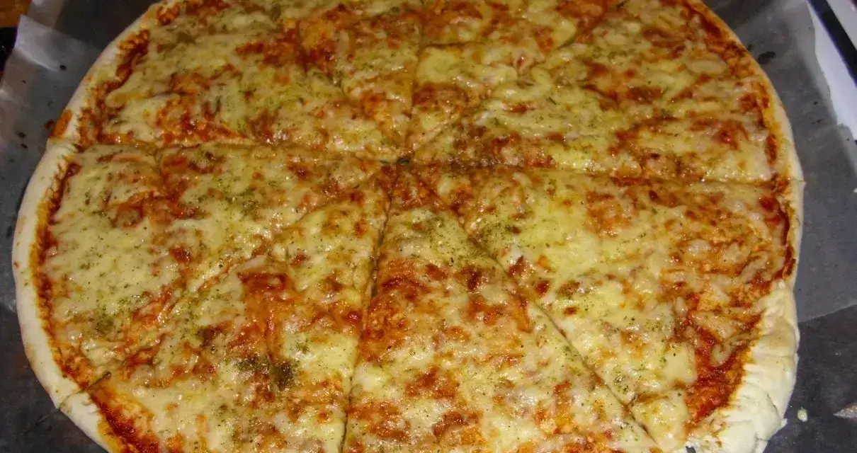 Pyszna, gorąca margerita z ciągnącym się serem i aromatycznymi ziołami, pokrojona na 8 kawałków.