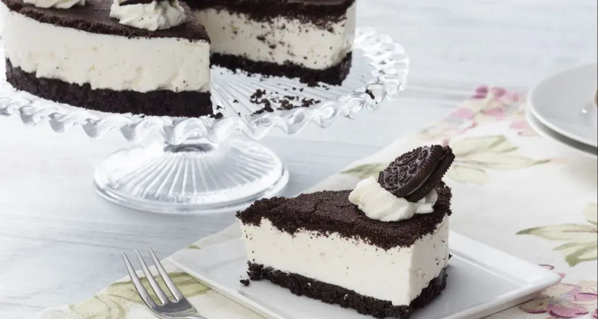 Una deliciosa tarta de oreo, con una base de galleta oscura y un cremoso relleno blanco, decorada con nata y galletas oreo.