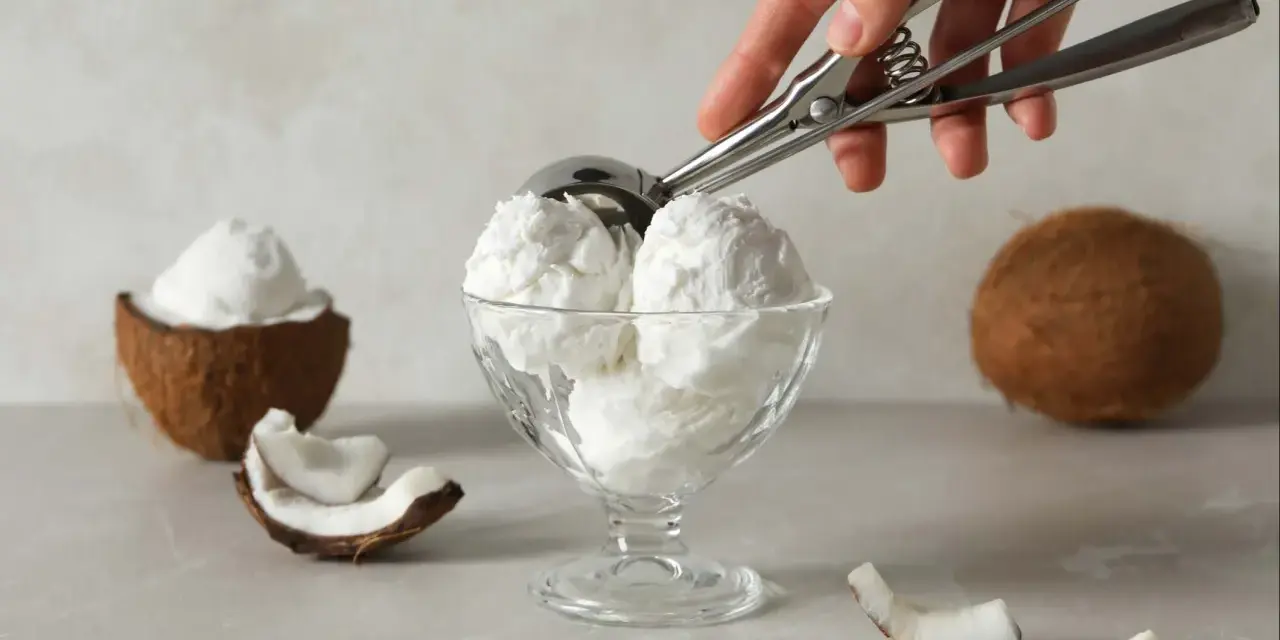 Copa de cremoso helado de coco, con trozos de coco fresco alrededor. ¡Un postre tropical!