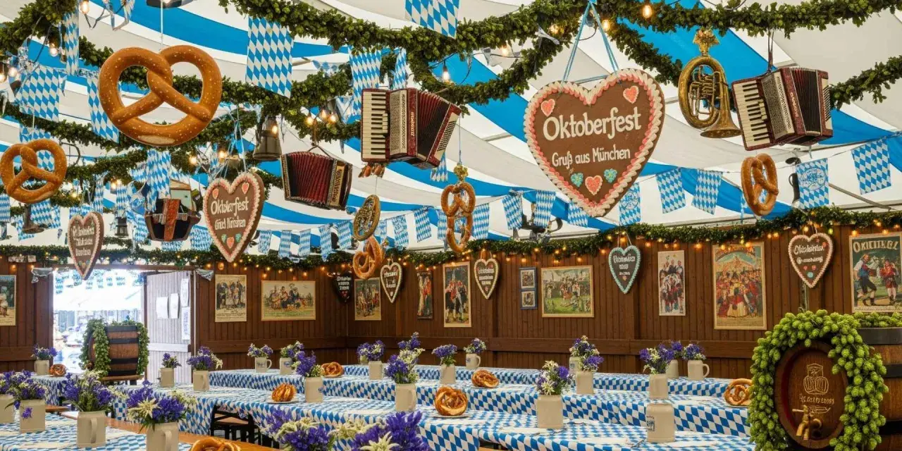 Wnętrze namiotu na Oktoberfest w Monachium. Wiszące precle, serca z piernika i akordeony. Stoły przykryte niebiesko-białymi obrusami, ozdobione kwiatami i kolejnymi preclami.