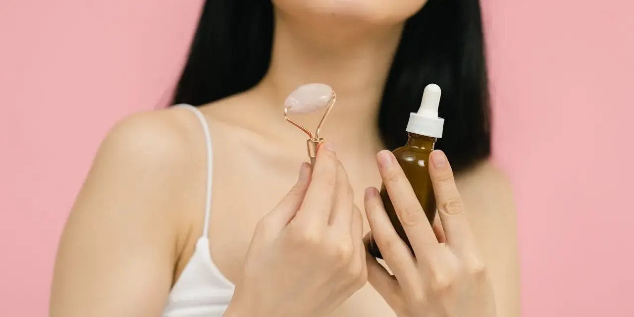 Uśmiechnięta kobieta z aparatem ortodontycznym trzyma jadeitowy roller i serum. Rozpoczyna wprowadzanie retinolu do swojej rutyny pielęgnacyjnej.