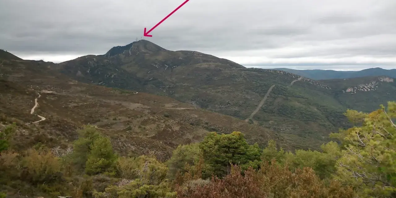 Un sendero serpentea hacia el **Pico del Águila**, coronado por antenas, bajo un cielo nublado.
