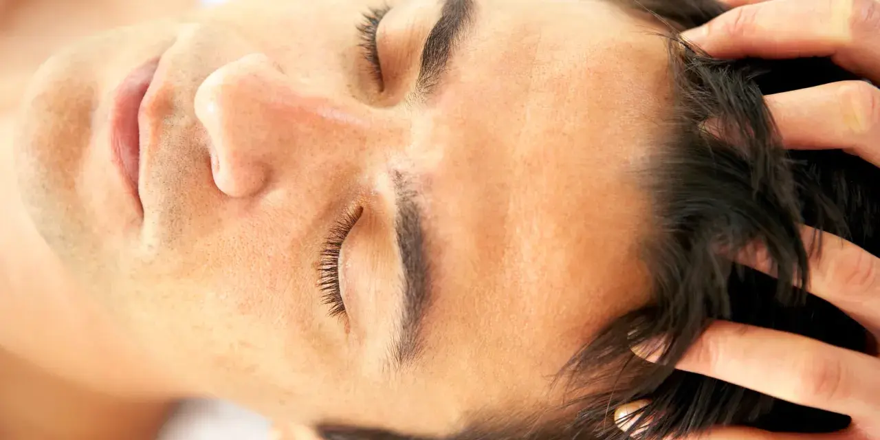 Fingers gently work through dark hair, demonstrating how to massage scalp for relaxation and hair health.