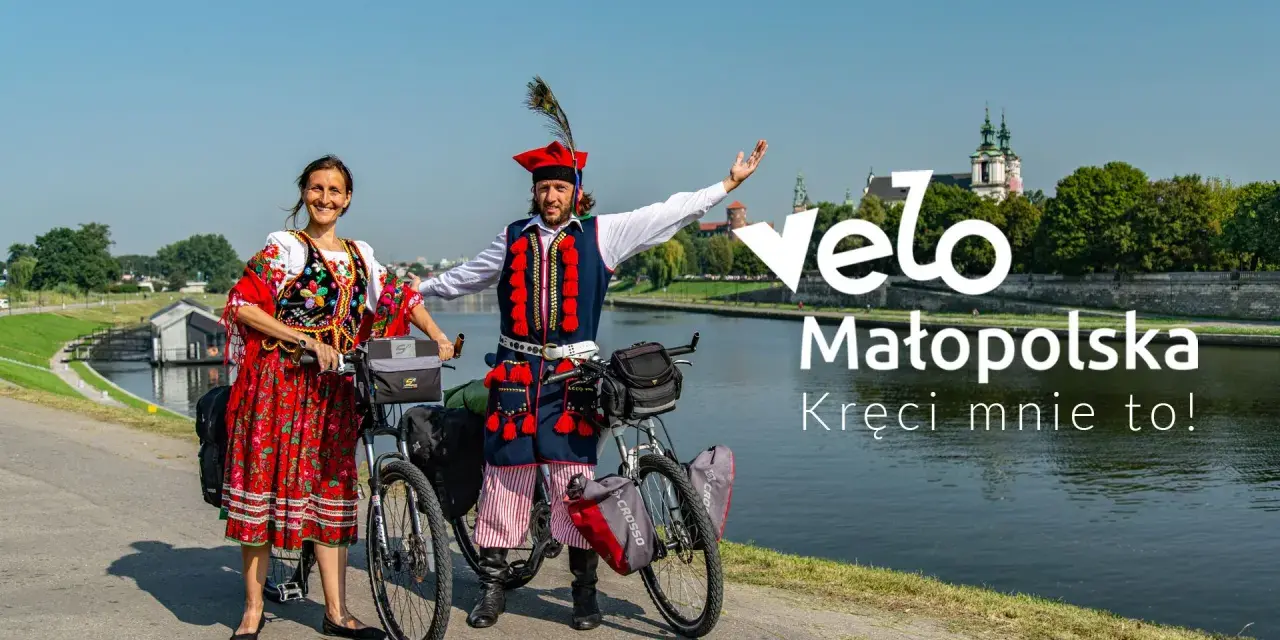 Para w strojach ludowych na rowerach nad Wisłą, promuje Velo Małopolska.